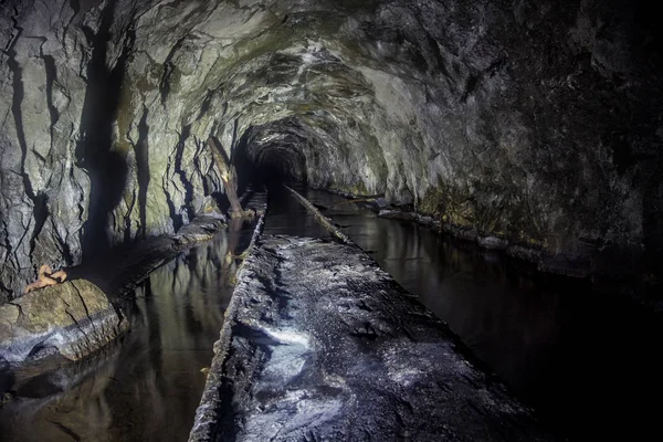 Flooded tunnel of an old abandoned coal mine with rusty remnants — Stock Photo, Image