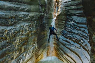 Şelale rappelling. Islıtakım elbiseli adam nar şelale üzerinde tırmanıyor