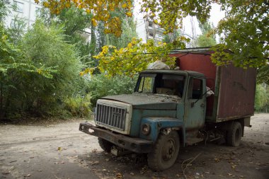 Terk edilmiş büyümüş kısmında kırık pencereleri ile eski paslı kamyon 