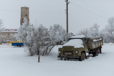 Terk edilmiş sanayi bölgesinde karla kaplı eski paslı kamyon 