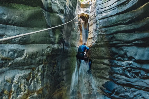 Wasserfall-Abseilen. Mann im Neoprenanzug klettert auf Wasserfall in Nar — Stockfoto