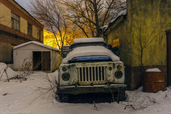 廃工業地帯の雪に覆われた古い錆びたトラック — ストック写真