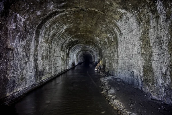 Översvämmad tunnel av en gammal övergiven kolgruva med rostiga rester — Stockfoto