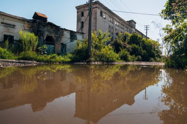 Terk edilmiş binalar yağmur suyu havuzuna yansıdı