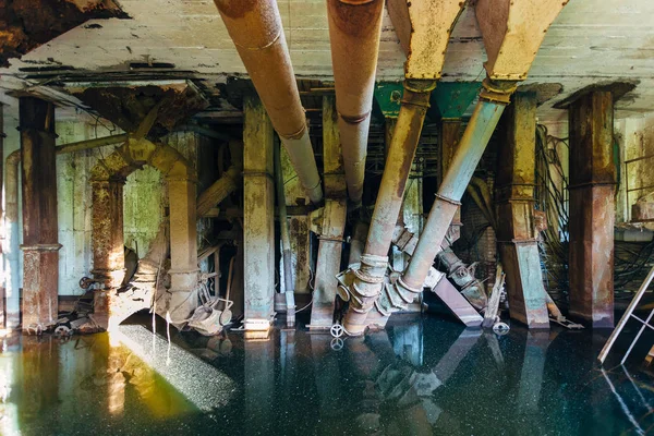 Inundada fábrica arruinada abandonada. Viejas tuberías oxidadas en agua sucia — Foto de Stock