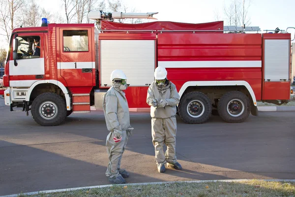 Двоє чоловіків у комплекті хімічного захисту на фоні пожежної машини — стокове фото