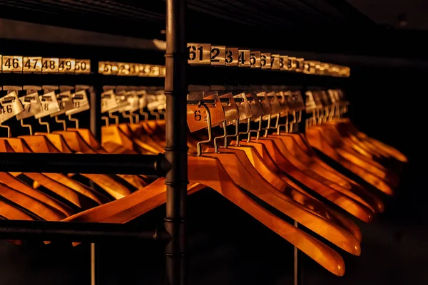 Perchas de madera con números en guardarropa oscuro — Foto de Stock