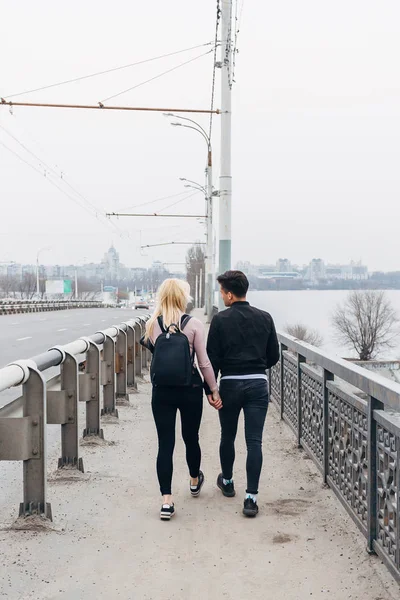 Jeune couple marchant en tenant la main sur le pont. Vue arrière — Photo