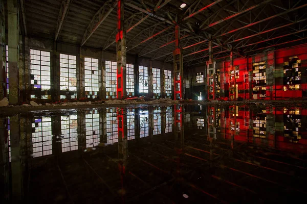 Grande salle industrielle abandonnée inondée éclairée par la lumière rouge — Photo