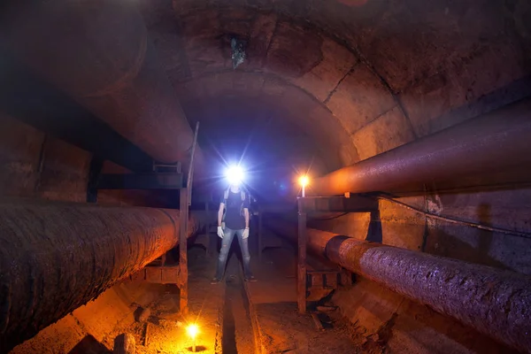 Urban explorer with candle in underground communication, heating — Stock Photo, Image