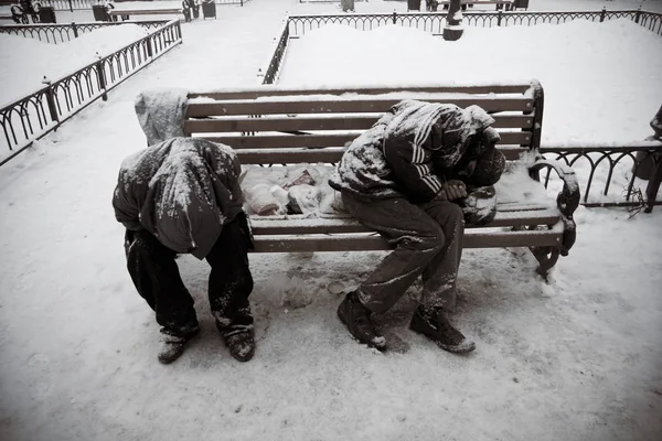 Unknown homeless people sleeping on the bench in winter park