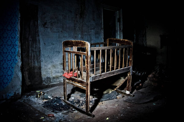 Old creepy eerie wooden baby crib in abandoned house. Horror con