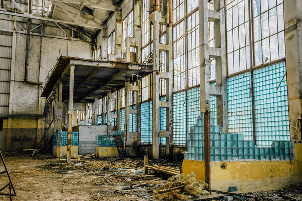 Abandoned large industrial hall. Broken wall from glass blocks.