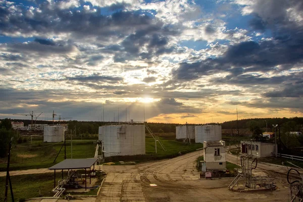 Gün batımı arka planında uçaklara yakıt ikmali için yakıt depolama tankları — Stok fotoğraf