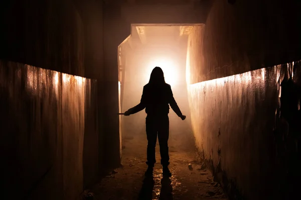 Silhouette effrayante avec couteau dans le bâtiment sombre abandonné. Ho ! — Photo