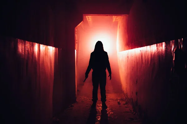 Silhouette effrayante avec couteau dans l'abandon lumineux rouge foncé — Photo