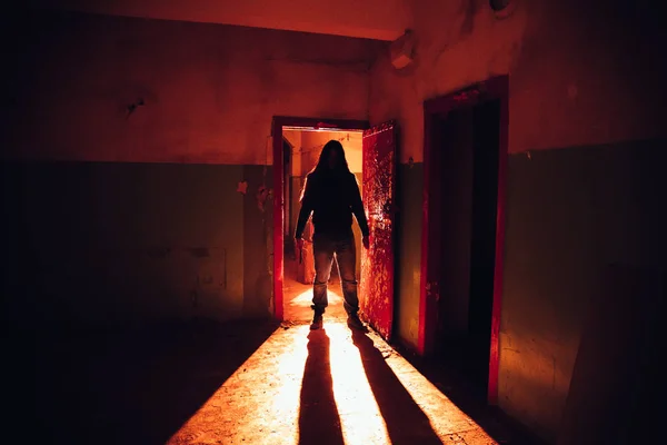 Silhouette effrayante avec couteau dans l'abandon lumineux rouge foncé — Photo