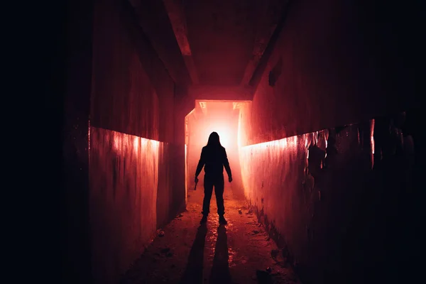 Creepy silhouette with knife in the dark red illuminated abandon — Stock Photo, Image