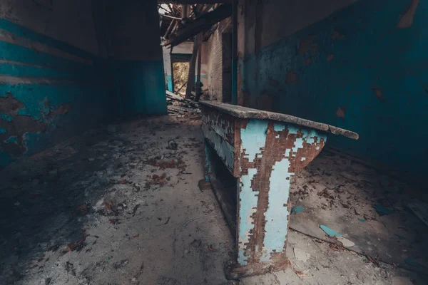 Old rotten blue desk in abandoned school corridor