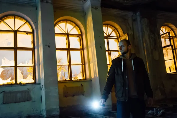 Hombre con linterna en oscuro espeluznante mansión abandonada por la noche —  Fotos de Stock