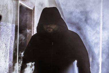 Karanlık, kasvetli koridorda sigara içen ya da buharlaşan adam silueti. 