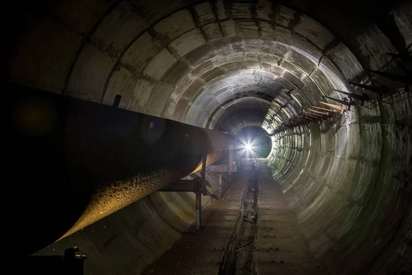Stary, brudny podziemny tunel techniczny z zardzewiałym rurociągiem — Zdjęcie stockowe