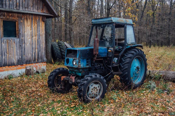 Stary zardzewiały niebieski traktor w drewnie. Rosyjska wioska. — Zdjęcie stockowe