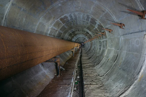 Old round dirty underground technical tunnel of heating duct wit