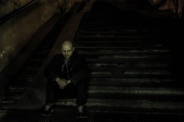 Karanlık sokak metrosunun merdivenlerinde oturan depresif üzgün adam. D