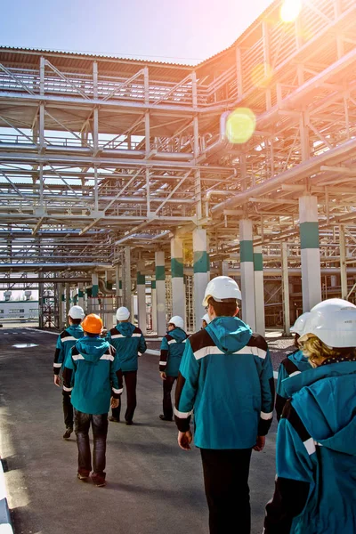 Працівники хімічного заводу в робочому одязі гуляють поблизу великого — стокове фото