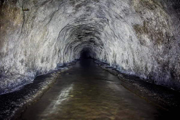 Затопленный туннель старой заброшенной угольной шахты с ржавыми остатками — стоковое фото