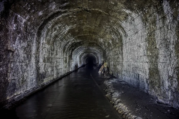 Затопленный туннель старой заброшенной угольной шахты с ржавыми остатками — стоковое фото