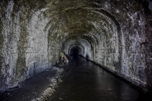 Översvämmad tunnel av en gammal övergiven kolgruva med rostiga rester — Stockfoto