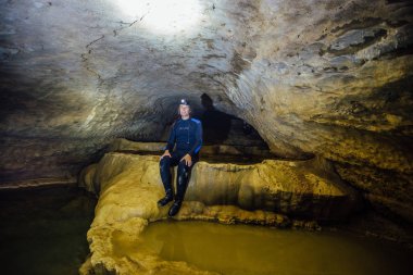 Dalgıç kıyafetli, farlı mutlu turist speleologu. 