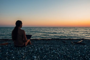 Akşam gün batımında dizüstü bilgisayar ile çalışan midilli masalı ile genç adam