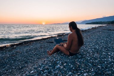 Akşam gün batımında dizüstü bilgisayar ile çalışan midilli masalı ile genç adam