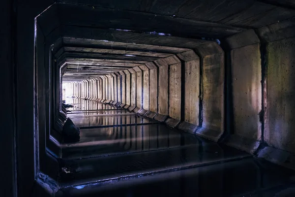 Luz al final del oscuro túnel de alcantarillado sucio inundado. Giro del tun — Foto de Stock