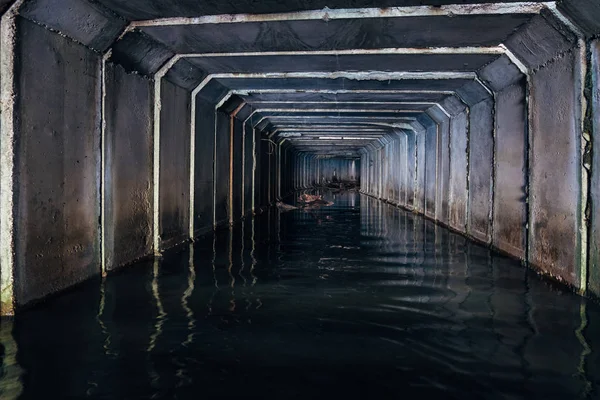 Zalany tunel kanalizacyjny odbija się w wodzie. Brudne ścieki miejskie — Zdjęcie stockowe
