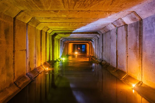 Túnel de alcantarillado rectangular inundado con aguas residuales urbanas sucias illumin —  Fotos de Stock
