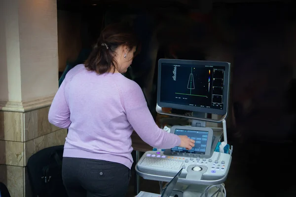 Female doctor adjusts ultrasound scan equipment for sonography diagnostics