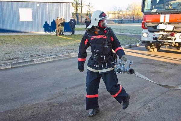 Пожежник з водяним шлангом біля пожежної машини — стокове фото