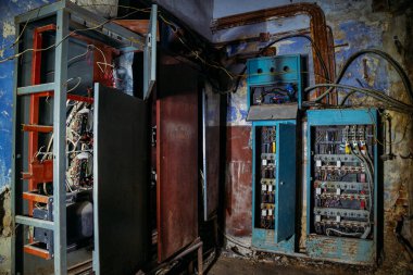 Terk edilmiş binada kontrol panelleri olan kırık elektrik şalter dolapları.
