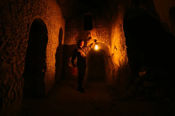 Człowiek z lampą naftową bada starożytne opuszczone podziemne katakumby klasztorne — Zdjęcie stockowe