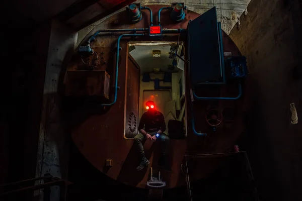 Creepy masked man in gateway corridor of airlock of abandoned bunker.