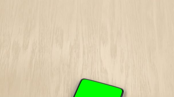 木製の机の上に緑の画面を持つモダンなスマートフォン — ストック動画