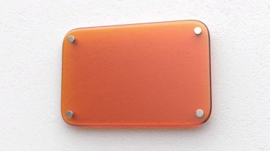 Orange glass nameplate on white wall