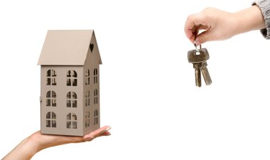 Evi tutan el, beyaz arka planda anahtarı olan çocuk eli.