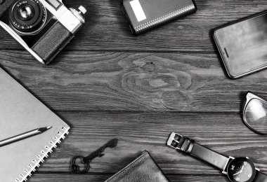 Siyah saat, siyah kalem, defter, kamera çantası ve telefon beyaz arkaplanda.