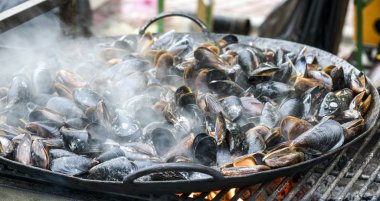 Büyük demir tabakta kızarmış deniz midyeleri.