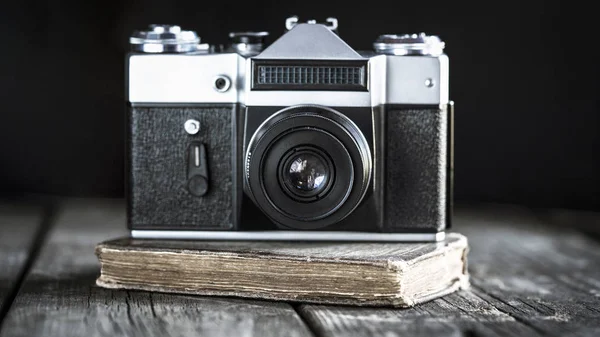 Photo camera and old diary on a wooden background